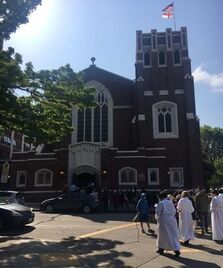 Brick church congregation outside on the street processing toward the entry