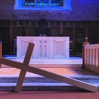 Large wooden cross lying on its side in front of a church altar